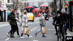 U.K. – Shoppers, some wearing a face mask or covering due to the COVID-19 pandemic, walk across a quiet road in central London on December 22, 2020.