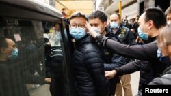 Stand News Acting Chief Editor Patrick Lam is escorted by police after a search of his office in Hong Kong, December 29, 2021. (Tyrone Siu/Reuters)