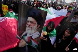 Demonstrators carry a huge Iranian flag and posters of the Supreme Leader Ayatollah Ali Khamenei during the annual rally commemorating Iran's 1979 Islamic Revolution, in Tehran on February 23, 2023. (Vahid Salemi/AP)