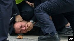 Policemen pin down and arrest a protester during a protest on a street in Shanghai, China, Sunday, Nov. 27, 2022.