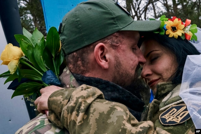 Ukrainian army medics Eugenia and Oleksander embrace after their wedding ceremony in Lyman on December 24, 2022. (Libkos/AP)