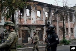Ukrainian servicemen pass a heavily damaged building in a recaptured area of Izyum on September 14, 2022. (Leo Correa/AP)