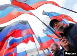 People carry flags of Russia and the self-proclaimed Donetsk People's Republic during a rally marking the 7th anniversary of the referendum on secession in the city of Donetsk on May 11, 2021. (Alexander Ermochenko/Reuters)
