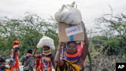Locals residents carry boxes and sacks of food distributed by the United States Agency for International Development (USAID), in Kachoda, Turkana area, northern Kenya, July 23, 2022.
(AP Photo/Desmond Tiro)