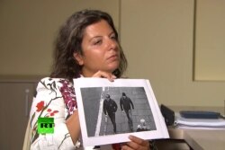 RT Editor-in-Chief Margarita Simonyan shows an image of two men during an interview with 'Alexander Petrov' and 'Ruslan Boshirov,' who are suspected by British authorities of poisoning former Russian spy Sergei Skripal and his daughter Yulia. (RT/TASS)