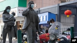 Statues with masks placed on them can be seen as a World Health Organization team visits Wuhan on February 9, 2021, to investigate origins of the COVID-19 pandemic. (Ng Han Guan/AP)