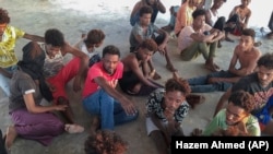 Rescued migrants sit on a coast some 100 kilometers (60 miles) east of Tripoli, Libya, Thursday, July 25, 2019. (Hazem Ahmed/AP)