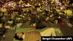 UKRAINE – Ukrainian woman lies down in front of Dutch embassy holding a poster reading "Putin is a killer," in Kyiv, July 17, 2014