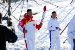 Qi Fabao, a regimental commander in the People's Liberation Army, relays the Olympic flame at the Winter Olympic Park in Beijing on February 2, 2022. (Reuters)