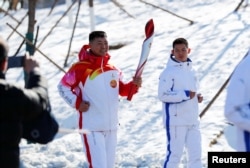 Qi Fabao, a regimental commander in the People's Liberation Army, relays the Olympic flame at the Winter Olympic Park in Beijing on February 2, 2022. (Reuters)