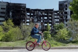 A boy rides a bicycle near a residential building destroyed during the Russian-Ukraine war in Mariupol on May 11, 2022. (Alexander Ermochenko/Reuters)