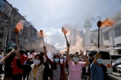 A group of women hold torches as they protest against the military coup in Yangon on July 14, 2021.