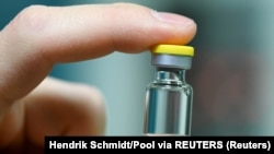 A worker of German vaccine maker IDT Biologika shows a sample ampoule during the visit of German Health Minister Jens Spahn in Dessau Rosslau, Germany, November 23, 2020.