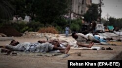 Homeless people sleep on a roadside during a smart lockdown of the Sindh province in Karachi, Pakistan, on 01 June 2021.
