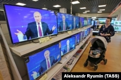 RUSSIA -- A woman walks past the TV screens in a shop during Russian President's annual nationwide televised phone-in show in Ryazan, June 20, 2019