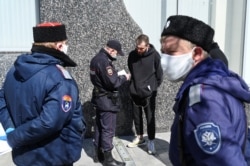 RUSSIA -- A Russian police officer checks the documents of a pedestrian as Cossacks stand nearby as they patrol a district, after local authorities tightened up measures to prevent the spread of the coronavirus disease (COVID-19), in Rostov-on-Don, April