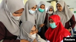 A college student reacts as she receives a vaccine dose against COVID-19 during a mass vaccination program at a campus in Lhokseumawe, Aceh province, on September 14, 2021. (Antara Foto/Rahmad/via Reuters)

