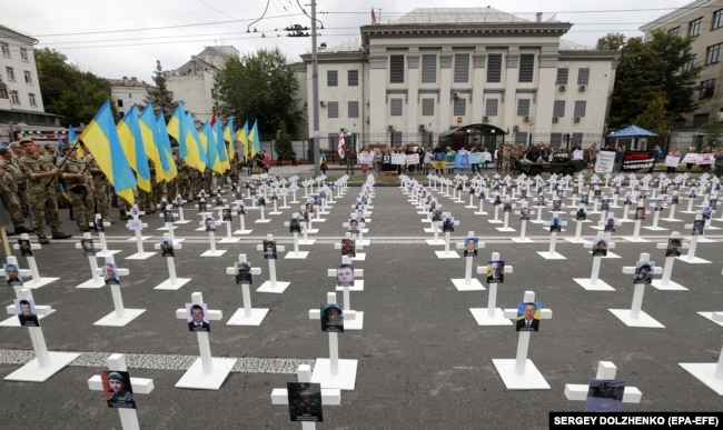 UKRAINE – Men in uniforms hold national flags near symbolic crosses with portraits of soldiers, who were lost near the village of Ilovaysk in eastern Ukraine in 2014, in front of Russian embassy in Kyiv, 29 August 2018