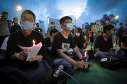 HONG KONG -- Hong Kong democracy activist Joshua Wong, center, holds a candle as he joins others for a vigil to remember the victims of the 1989 Tiananmen Square Massacre at Victoria Park in Causeway Bay, Hong Kong, Thursday, June 4, 2020.