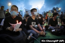 HONG KONG -- Hong Kong democracy activist Joshua Wong, center, holds a candle as he joins others for a vigil to remember the victims of the 1989 Tiananmen Square Massacre at Victoria Park in Causeway Bay, Hong Kong, Thursday, June 4, 2020.