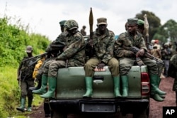 M23 rebels prepare to leave after a ceremony to mark the withdrawal from their positions in the town of Kibumba, in the eastern of Democratic Republic of Congo. (AP Photo/Moses Sawasawa)