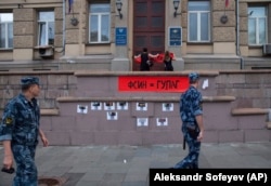 RUSSIA -- Activists of the feminist protest group Pussy Riot, fix a poster reading ' Federal Penitentiary service = GULAG', on the wall of the Federal Penitentiary building in Moscow, August 7, 2018