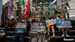 Activists stage a protest outside the Chinese Consulate, guarded by Philippine police, on the fifth anniversary of an international arbitral court ruling invalidating Beijing's historical claims over the waters of the South China Sea, in Makati City, Philippines on July 12, 2021.