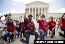 DACA recipients and their supporters take a knee in support of the Black Lives Matter movement, chanting "Say their Names" as they celebrate outside the U.S. Supreme Court after it rejected the Trump administration's atempt to end DACA.