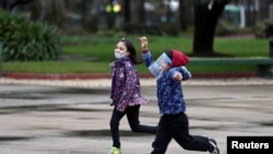 Children wearing protective face coverings play at a park as the government begins to ease quarantine restrictions imposed to slow the spread of the coronavirus disease (COVID-19), in Buenos Aires, Argentina July 23, 2020. REUTERS/Agustin Marcarian
