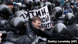 RUSSIA -- Riot police officers detain a protester holding a poster reading 'Putin, you are not my President' during a rally in St. Petersburg, January 28, 2018