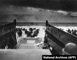 This June 6,1944 image courtesy of the National Archives shows U.S. Army troops wading ashore at Omaha Beach in France during the D-Day invasion.