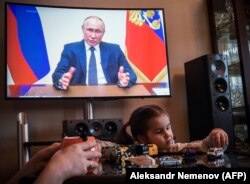 RUSSIA -- A woman watches a live broadcast of Russian President Vladimir Putin's address to the nation over the coronavirus outbreak, in her appartment in Moscow, April 2, 2020