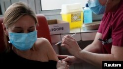 A member of the medical staff administers the Oxford-AstraZeneca COVID-19 vaccine to a colleague at the Foch hospital in Suresnes, near Paris, France, February 8, 2021.