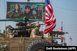 SYRIA -- A U.S. armored vehicle drives past a billboard for the Syrian Kurdish Women's Protection Units (YPJ), during a patrol of the Syrian northeastern town of Qahtaniyah at the border with Turkey, October 31, 2019