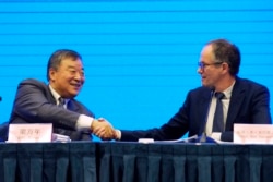 Peter Ben Embarek, of the World Health Organization team, right, shakes hands with his Chinese counterpart Liang Wannian after a WHO-China Joint Study Press Conference held at the end of the WHO mission in Wuhan, China, on Feb. 9, 2021.