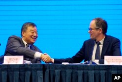 Peter Ben Embarek, of the World Health Organization team, right, shakes hands with his Chinese counterpart Liang Wannian after a WHO-China Joint Study Press Conference held at the end of the WHO mission in Wuhan, China, on Feb. 9, 2021.