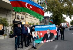People wave the national flag and hold portraits of Azerbaijani President Ilham Aliyev as they celebrate in the streets of the capital Baku, Azerbaijian on November 10, 2020. AFP.