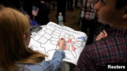 U.S. -- A girls colors an electoral map of the United States in either red or blue as returns are announced for the U.S. general election at election-night party, November 8, 2016.