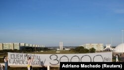 Artists hold a banner reading "Who's gone is someone's love, 30,000 dead" amid the coronavirus disease (COVID-19) outbreak in Brasilia