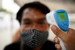 FILE PHOTO: A man wearing a protective face mask gets his temperature taken before receiving free food during the coronavirus disease (COVID-19) outbreak in Bangkok, Thailand, April 27, 2020.