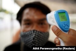 FILE PHOTO: A man wearing a protective face mask gets his temperature taken before receiving free food during the coronavirus disease (COVID-19) outbreak in Bangkok, Thailand, April 27, 2020.