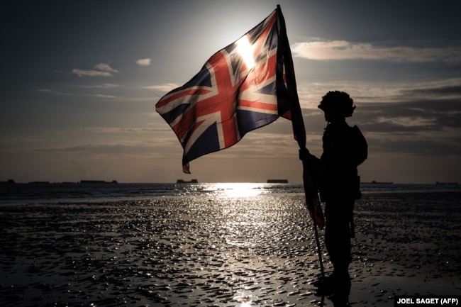 FRANCE -- This picture taken on June 6, 2019 shows the silhouette of a soldier holding an English flag on the beach of Arromanches, during the D-Day commemorations marking the 75th anniversary of the World War II Allied landings in Normandy.