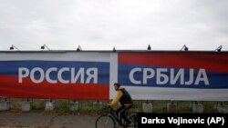 SERBIA -- A man rides bicycle pasts a billboards reading 'Russia' (left) and 'Serbia', in Belgrade, October 17, 2014