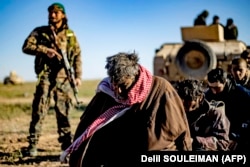 Men and boys suspected of being Islamic State (IS) group fighters wait to be searched by members of the Kurdish-led Syrian Democratic Forces (SDF) after leaving the IS last holdout of Baghouz, in the eastern Syrian Deir Ezzor province on March 1, 2019.