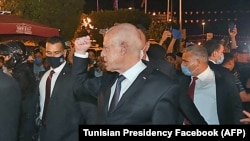 Tunisian President Kais Saied gesturing among supporters he walks protected by security in Tunis, July 26, 2021. ( Tunisian Presidency Facebook/AFP)
