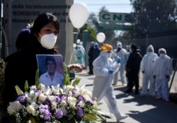 A woman holds a photo of late nurse Marcelino Lopez, who she said died of COVID-10 outside the CNS medical center where he worked in Cochabamba, Bolivia, Thursday, Aug. 6, 2020.