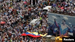 VENEZUELA – Opposition supporters take part in a rally against Venezuela's President Nicolas Maduro next to a poster of him in Caracas, Venezuela, October 26, 2016.