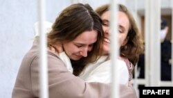 Belsat TV journalists Katsyaryna Andreyeva and Daryya Chultsova, who were detained in November while reporting on anti-government protests, embrace each other in a defendant's cage during their trial in Minsk, February 18, 2021.