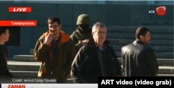 UKRAINE -- Reshat Ametov (right) stands near a masked Russian soldier in an unmarked uniform and a man wearing a red armband typical of the of the so-called "self-defense" forces shortly before his abduction at the Council of Ministers building, March 3