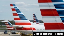 FILE PHOTO: A member of a ground crew walks past American Airlines planes parked at the gate at Ronald Reagan National Airport in Washington, U.S., April 5, 2020. 